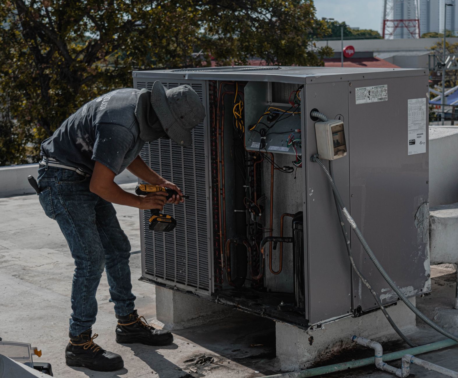 En tekniker arbejder ved en udendørs ventilationsenhed på et tag